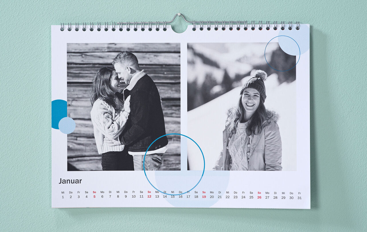 A mentazöld falon téli fekete-fehér fotókkal és kék színű kör alakú cliparttal díszített naptár lóg.