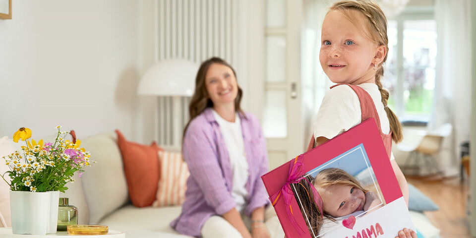 Egy kislány büszkén mutat egy CEWE FOTÓKÖNYVET, amin ő szerepel.
