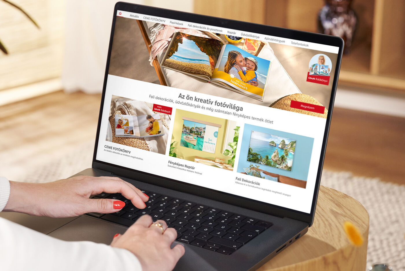 Személy laptopon dolgozik, míg CEWE fotótermékek weboldalát nézi.